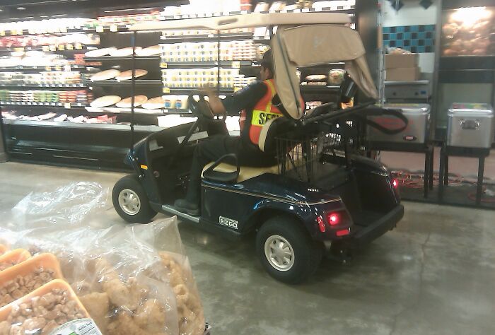 Security guard sitting in a golf cart inside a store, illustrating extreme laziness to feel better about taking a day off.