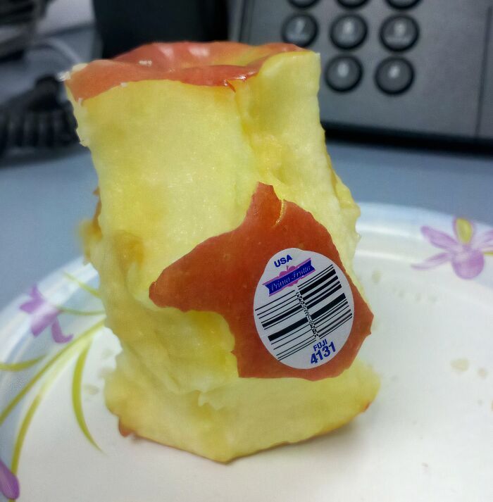 Partially eaten apple core with sticker on a plate, illustrating people who are so lazy they might inspire a day off.
