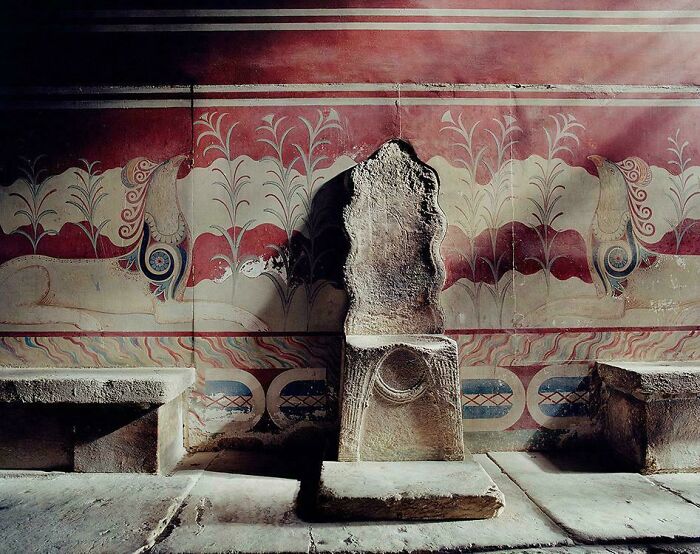 Ancient stone throne in a room with detailed wall paintings, showcasing antique items that reveal history secrets.