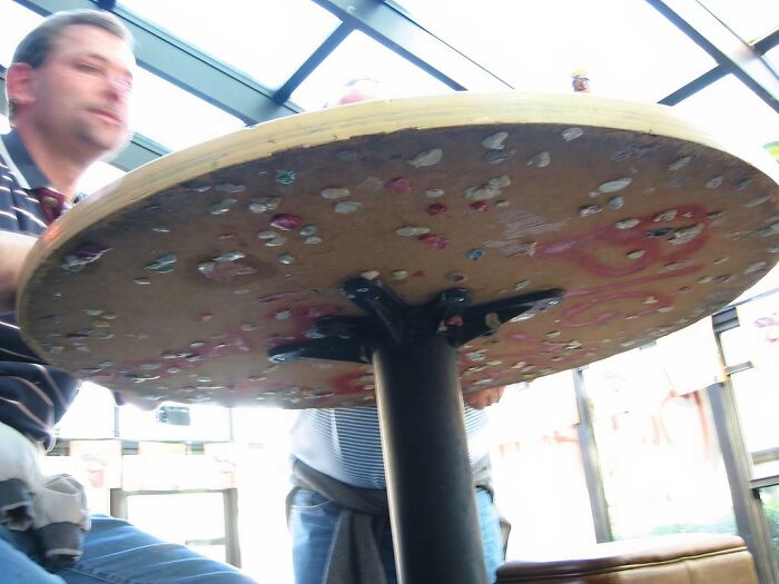 Two men sitting lazily at a round table in a bright room, illustrating people who are so lazy they might relate.