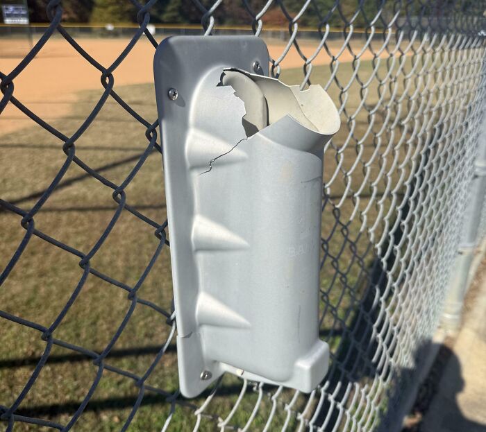 Damaged plastic device mounted on chain-link fence, illustrating an annoying little problem with outdoor tools and solutions.