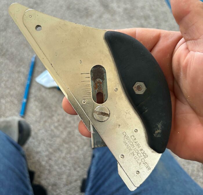 Hand holding a metal cutting tool with black grip, one of the interesting tools that might solve annoying little problems.