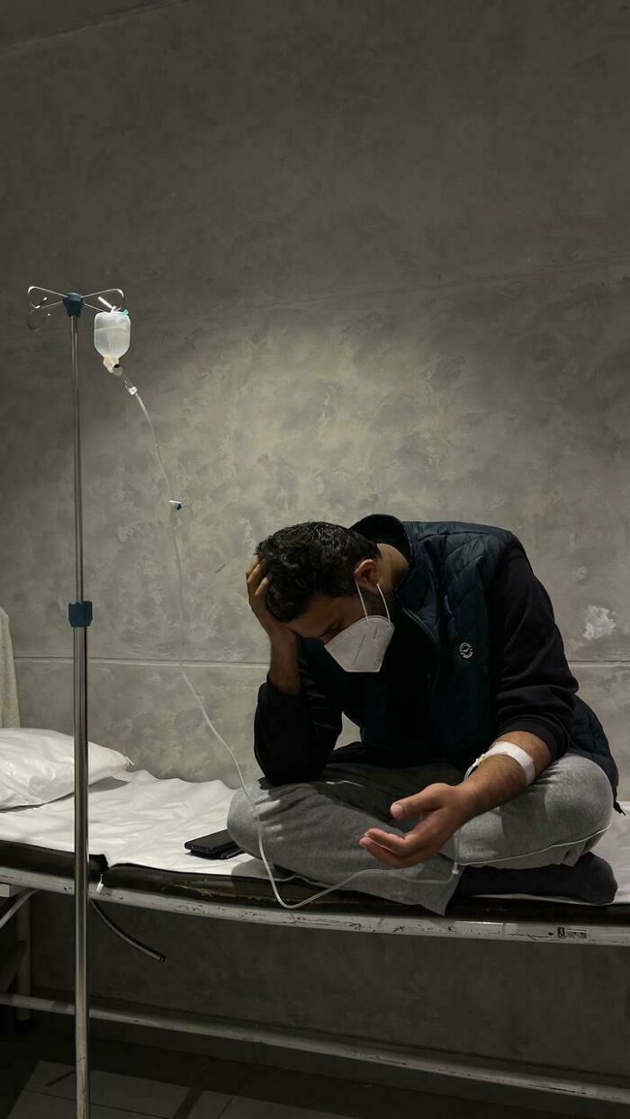 A weary man with an IV drip in a dimly lit room, capturing a somber Accidental Renaissance vibe.