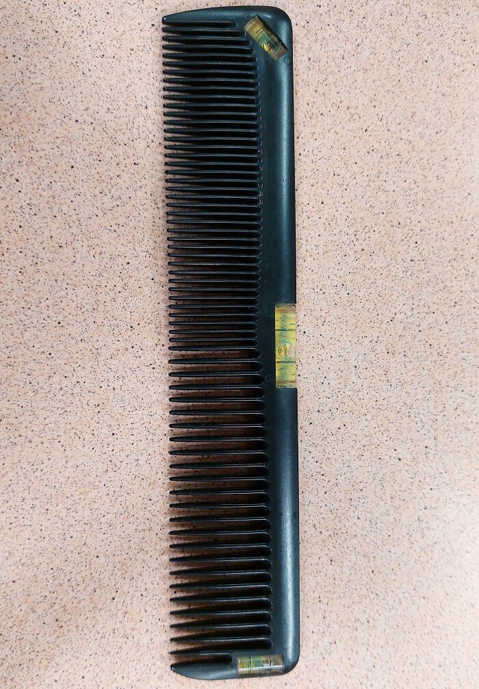 Black hair comb with wide and narrow teeth on a speckled surface, one of the interesting tools solving little problems.