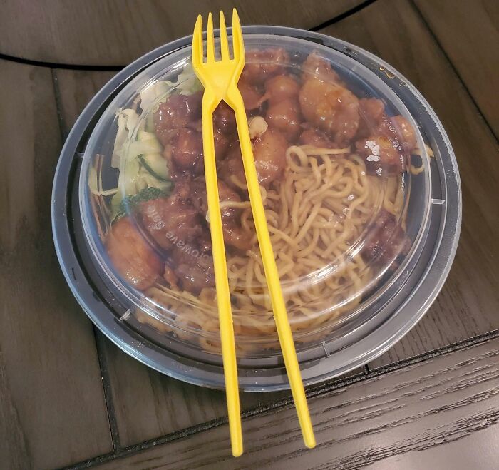 Plastic food container with lid and yellow multi-purpose tool fork resting on top, showcasing useful tools that solve small problems.