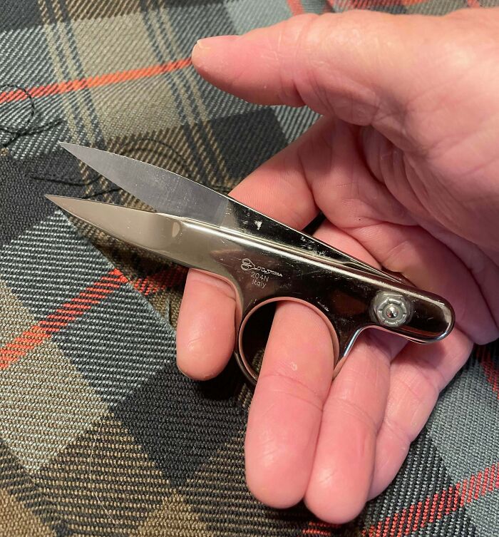 Hand holding a pair of sewing snips, an interesting tool that can solve an annoying little problem with fabric cutting.