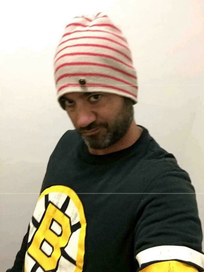 Man wearing a striped beanie and Boston Bruins shirt taking a selfie, showing a cringe unaware expression.