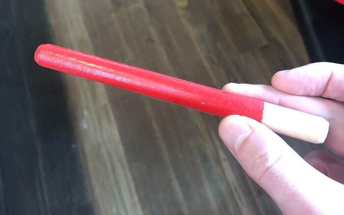 Hand holding a red and white tool designed to solve an annoying little problem with a clever solution.