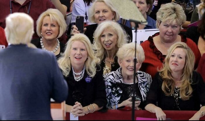 Group of women reacting awkwardly while listening to a man speak, capturing cringe moments in social interactions.