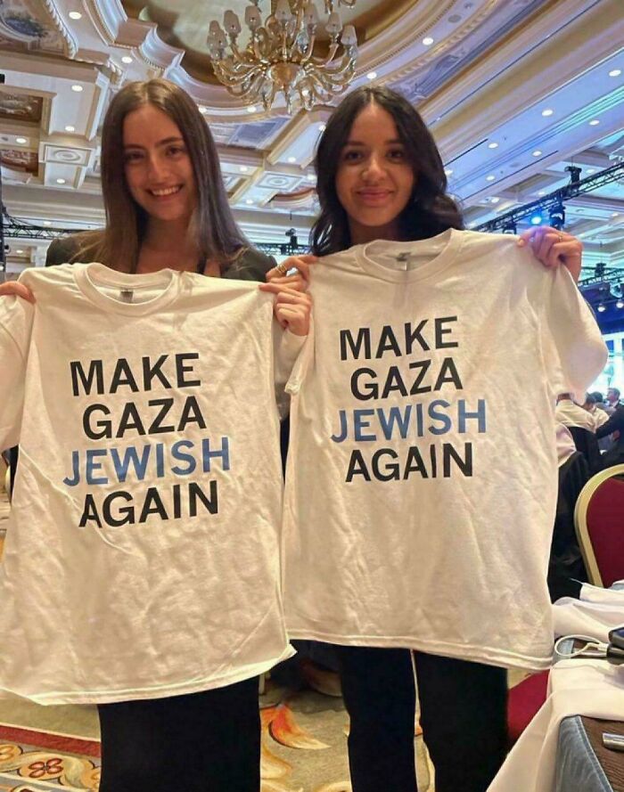 Two young women holding white shirts with the phrase "Make Gaza Jewish Again" in a crowded event setting, cringe moments.