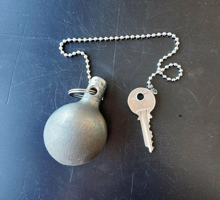 Metalworkers defying physics creating a key and heavy metal ball attached with a chain on a black surface.