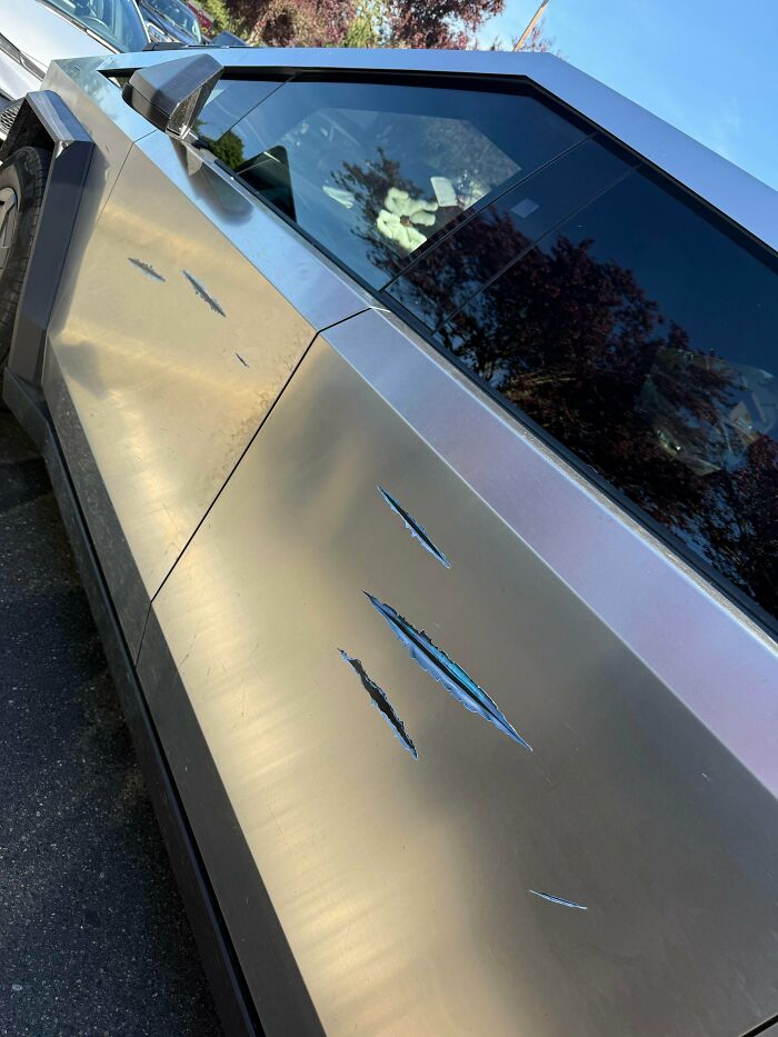 Silver car with scratched metal surface and visible dents, showing cringe moments from unaware people captured in new pics.