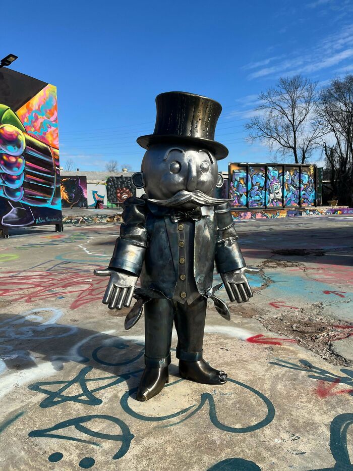 Metal sculpture of a cartoonish man with a top hat and mustache, showcasing metalworkers' remarkable creative skill.