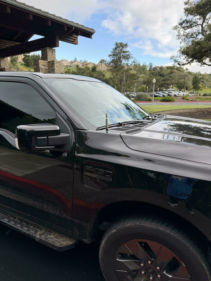 Black Ford F-150 truck parked outside with a pen awkwardly stuck in the windshield wiper, showcasing cringe moments.