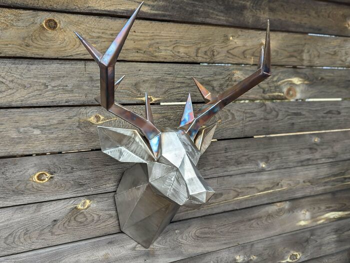 Metalworkers crafted a remarkable geometric metal deer head sculpture with intricate antlers mounted on wooden planks.