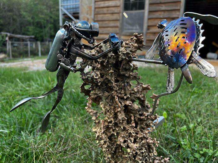 Metalworker sculpture of a diver interacting with a colorful mechanical fish, showcasing remarkable metalworking craftsmanship outdoors.