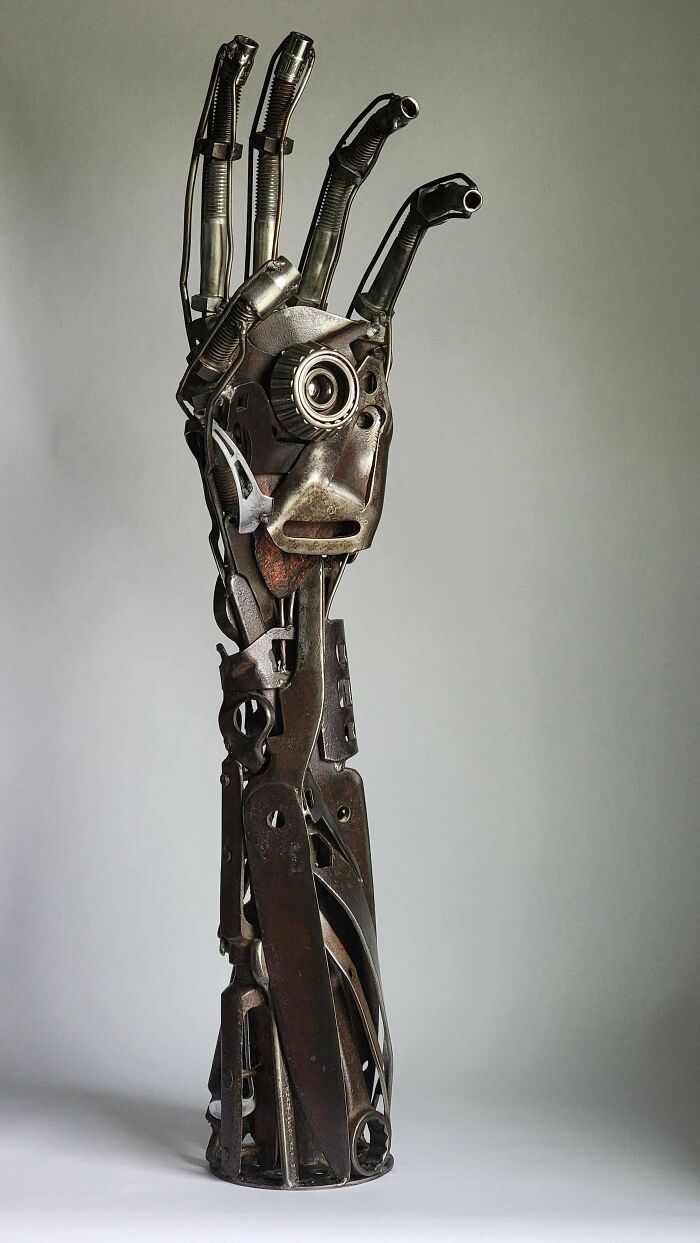 Sculpture of a robotic hand crafted by metalworkers showcasing remarkable skill defying physics and logic.