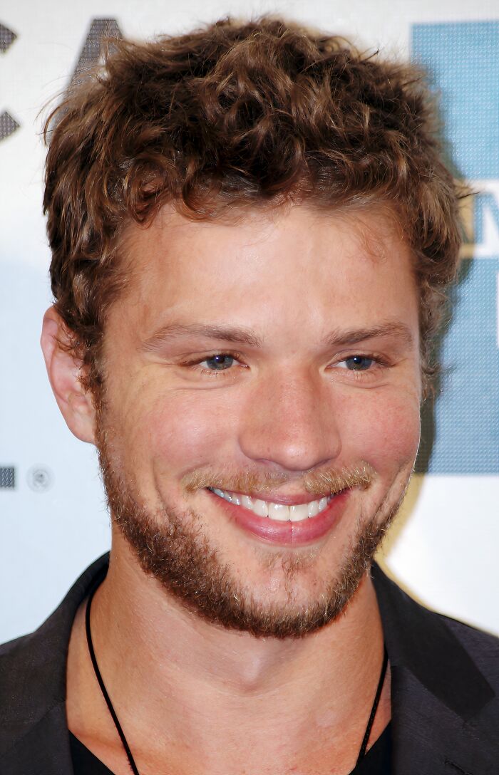 Close-up of an iconic actor with curly hair and beard smiling at a Hollywood event, representing actors who vanished suddenly.