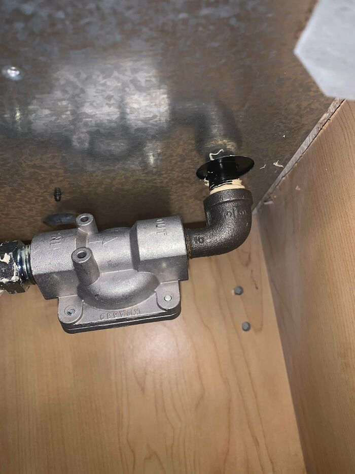 Metal gas valve with pipe under kitchen cabinet, related to odors you should never dismiss for safety reasons.