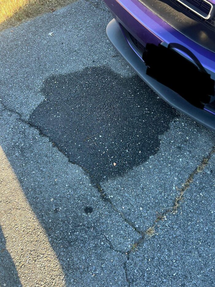 Car leaking fluid on pavement under front of purple car illustrating odors you should never dismiss.