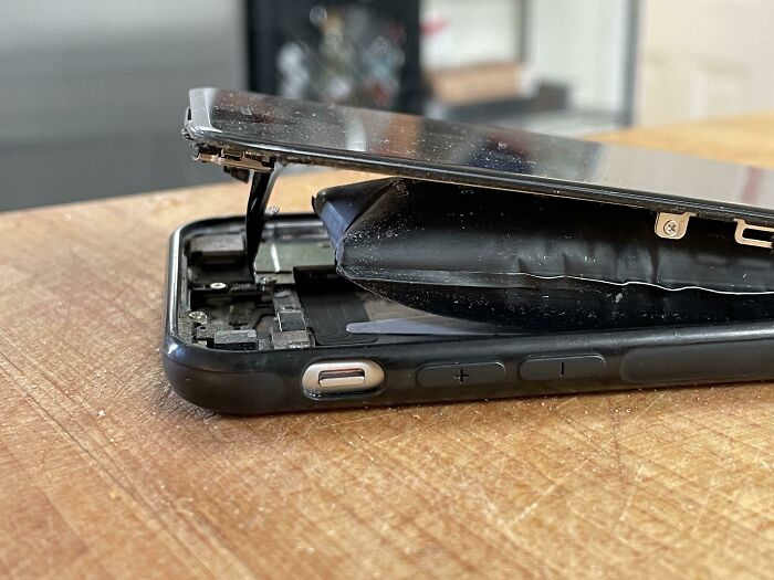 Swollen phone battery causing the device to split open, highlighting dangers you should never dismiss about odors.