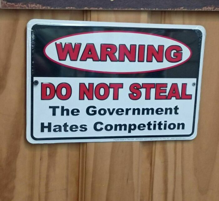 Warning sign on wooden door reads do not steal government hates competition strange humorous sign.