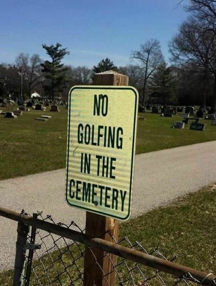 No golfing in the cemetery sign posted near gravestones and a pathway under a clear blue sky showing strange signs.