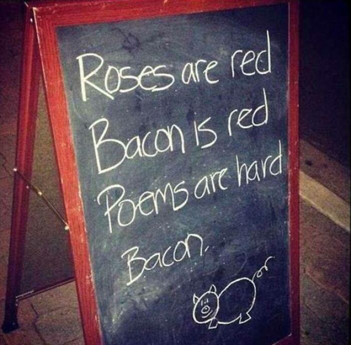 Chalkboard sign with a humorous poem about bacon and a simple pig drawing in a dimly lit setting.