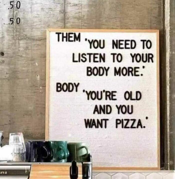 Humorous sign on a wall contrasting advice to listen to your body with a funny pizza craving message.