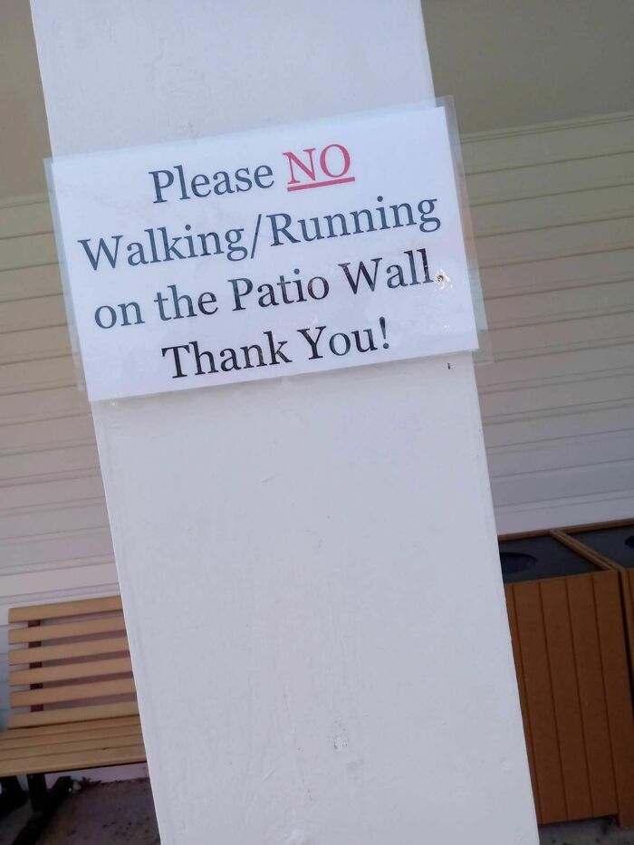 Strange sign forbidding walking or running on a patio wall, part of 77 signs so strange they deserve a double take.