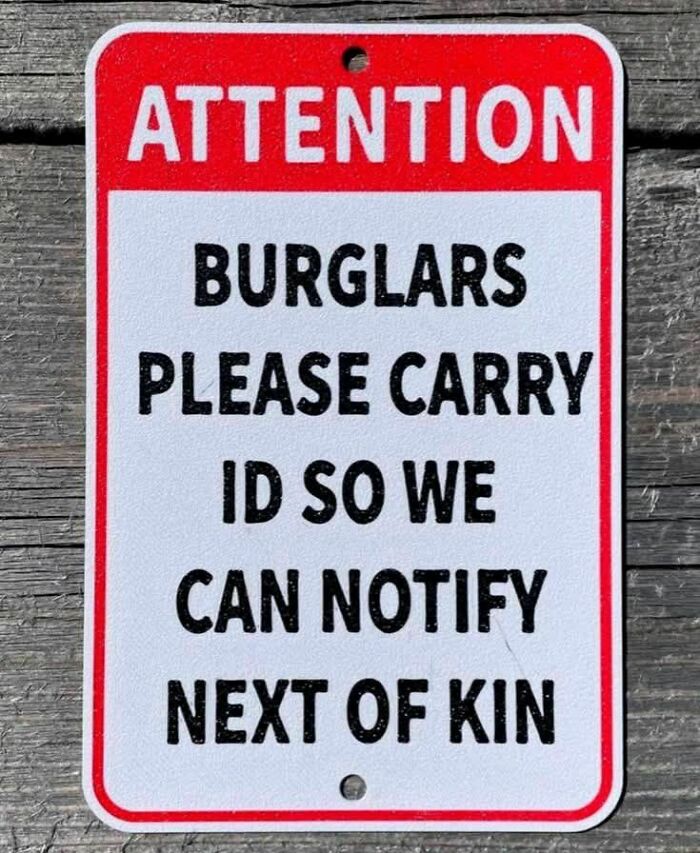 Red and white strange sign humorously asking burglars to carry ID for next of kin notification, a strange sign to double take.