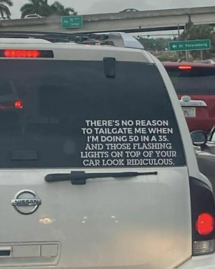 White Nissan SUV with a humorous weird sign about tailgating and flashing lights, one of the strange signs to double take.
