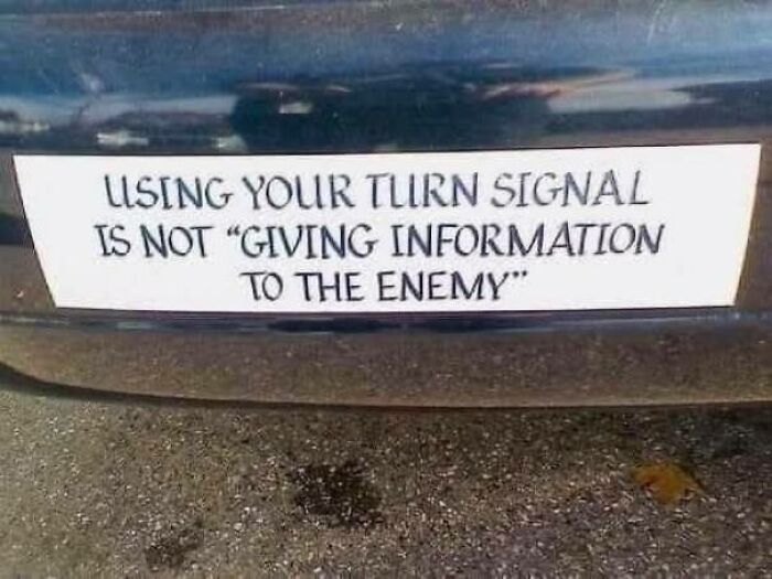 Bumper sticker with a strange sign saying using your turn signal is not giving information to the enemy.