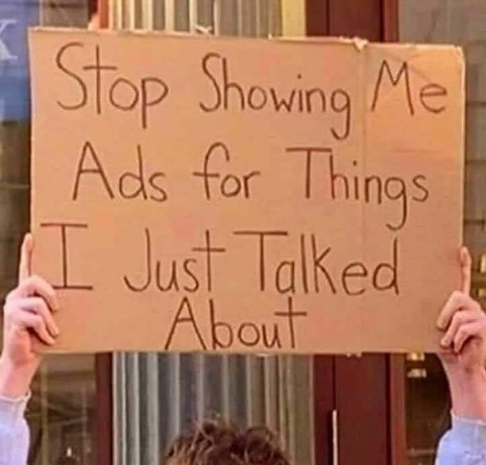 Person holding a strange sign that reads stop showing me ads for things I just talked about in a public setting