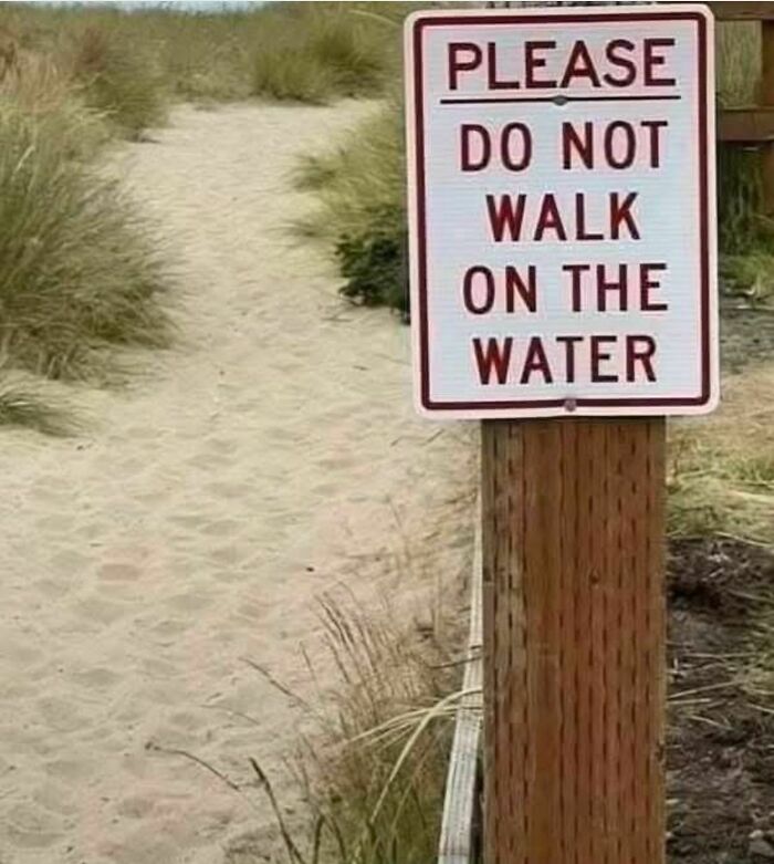 Unusual and strange sign on a sandy path warning visitors not to walk on the water.