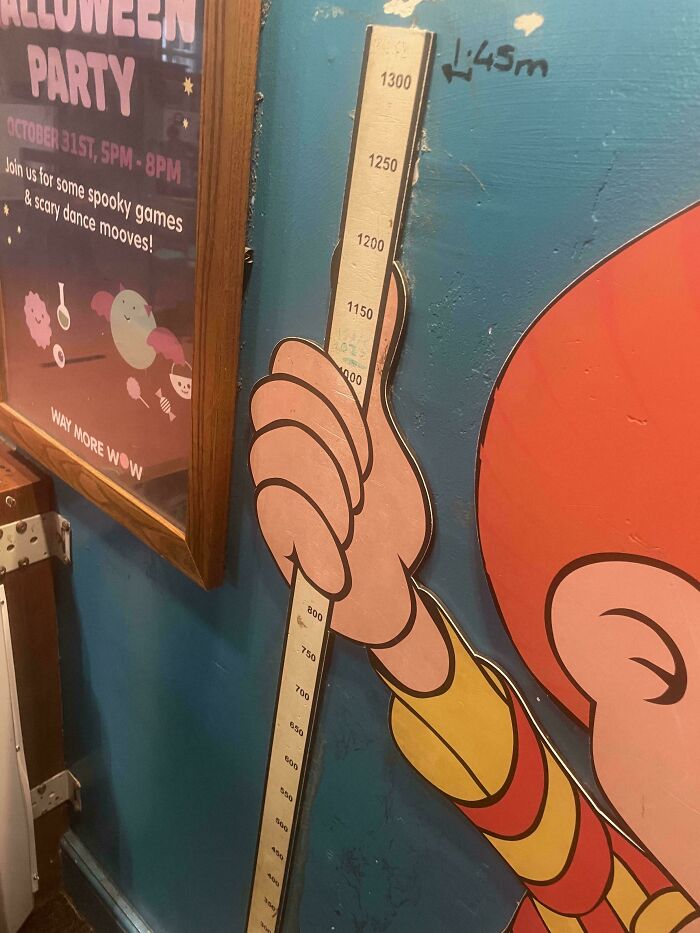 Height measurement chart shaped like a hand holding a ruler, an example of terrible product designs in public spaces.