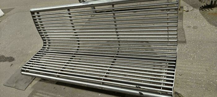 Metal bench with uneven seating bars creating an uncomfortable design flaw, an example of terrible product designs.