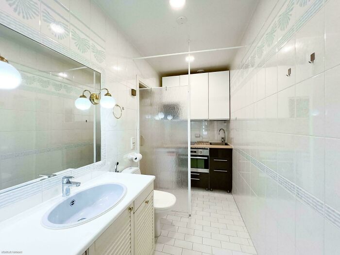 Small bathroom with unclear shower partition and kitchen appliances visible, showcasing terrible product design flaws.