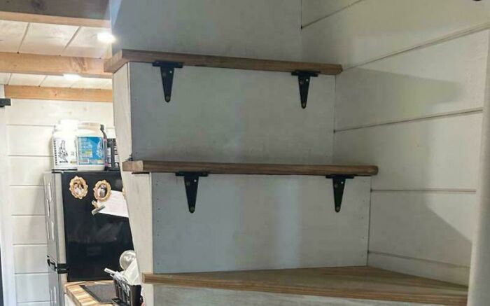 Stacked wooden shelves on a wall with poor structural design creating an unstable and impractical setup for everyday use.