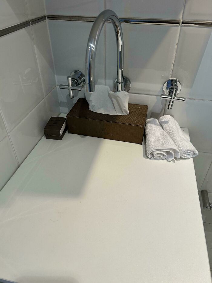 Faucet placed directly over tissue box making it unusable, showing one of the terrible product designs in a bathroom setup.