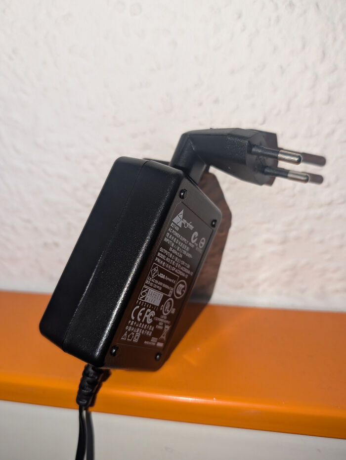 Power adapter plugged into a wall socket at an awkward angle, showcasing terrible product design flaws.