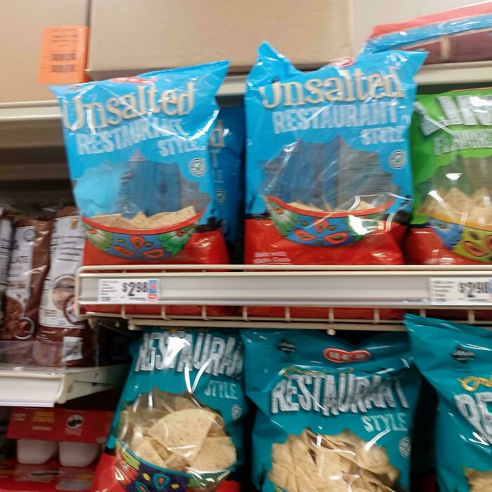 Grocery shelf with poorly designed chip bags featuring a large transparent window that makes the bag look empty.