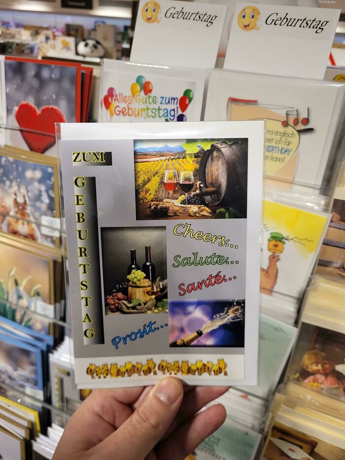 Hand holding a birthday card with awkward collage design showcasing drinks and cheers text, illustrating terrible product designs.