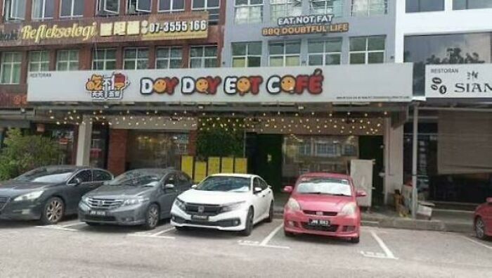 Parking spots labeled for a café with confusing sign design contributing to terrible product designs visible outside the building.