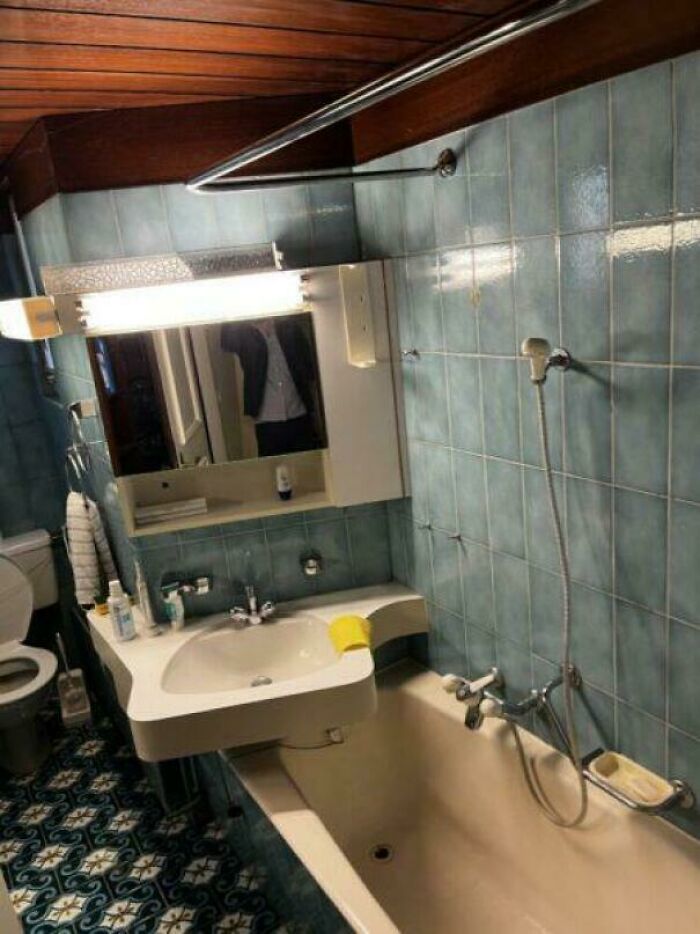Small bathroom with a sink awkwardly overlapping the bathtub, showcasing terrible product design flaws.