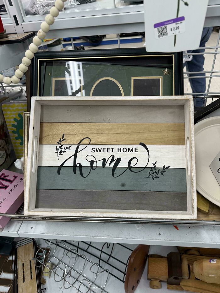 Wooden tray with the misspelled phrase "Sweet Home Home" displayed among other home decor, a terrible product design example.