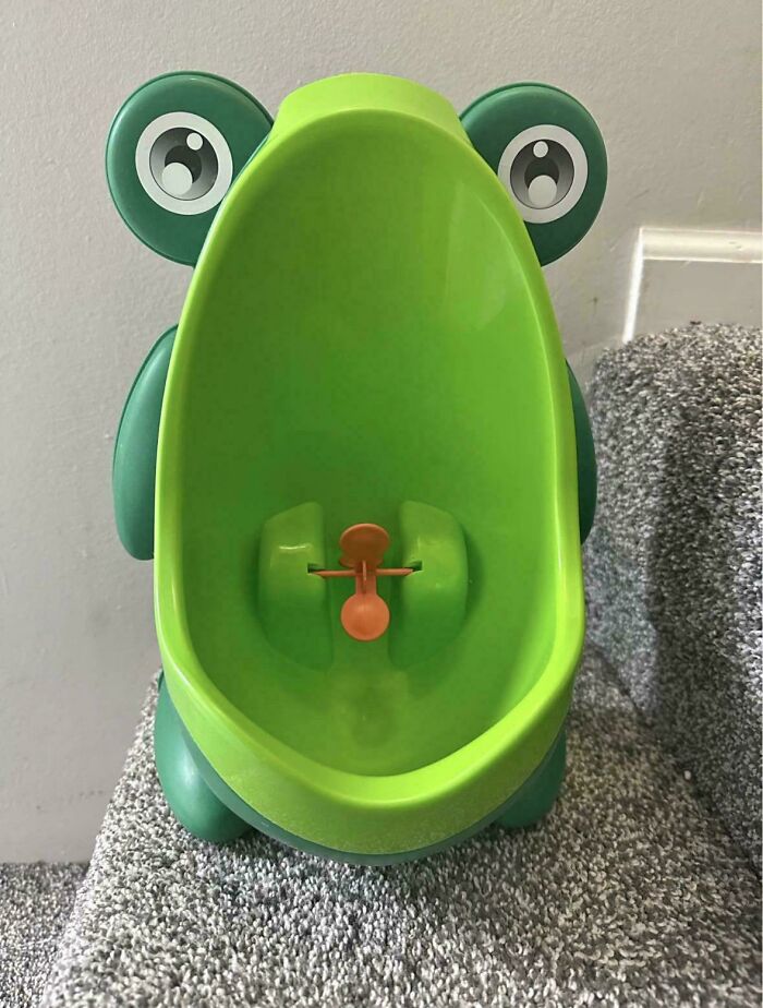 Green frog-shaped toddler urinal with a spinning wheel inside, an example of terrible product designs.