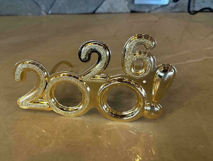 Gold-colored 2026 glasses with hollow lenses, showcasing a terrible product design flaw in the numbers and structure.