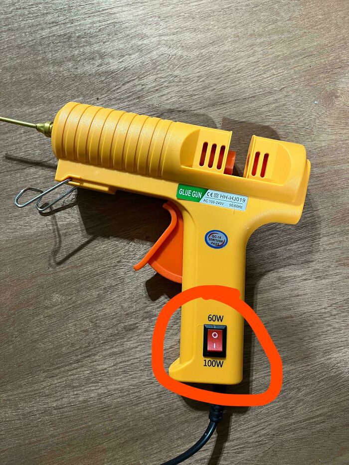 Yellow glue gun with a power switch labeled 60W and 100W, highlighting a terrible product design flaw.