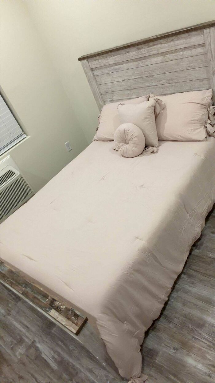 A bedroom featuring a light pink bed with a rustic wooden headboard, a cozy home decor project.